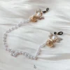 "Stellar Nipple Heart Bell Noose: A pair of heart-shaped nooses with bells and a pearl-inspired connecting chain, available in gold and silver."