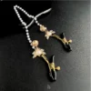 "Stellar Nipple Heart Bell Noose: A pair of heart-shaped nooses with bells and a pearl-inspired connecting chain, available in gold and silver."