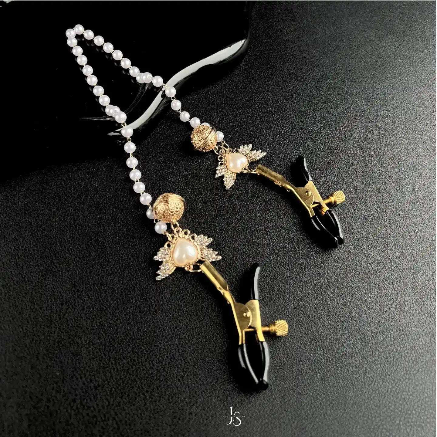 "Stellar Nipple Heart Bell Noose: A pair of heart-shaped nooses with bells and a pearl-inspired connecting chain, available in gold and silver."