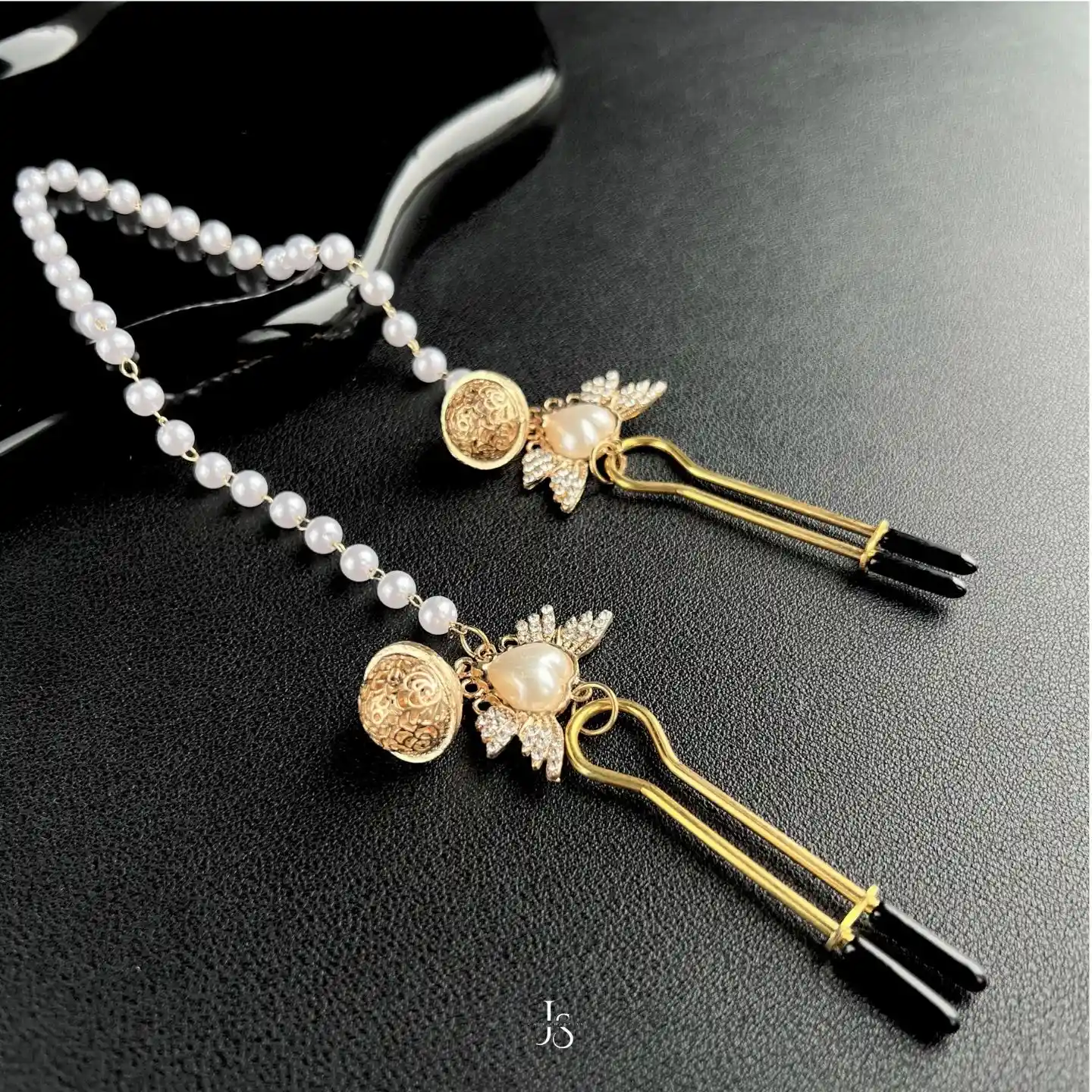 "Stellar Nipple Heart Bell Noose: A pair of heart-shaped nooses with bells and a pearl-inspired connecting chain, available in gold and silver."
