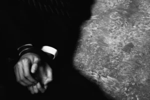 man in suit with hands cuffed on the ground