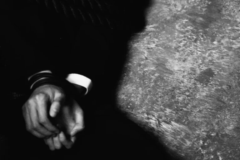 man in suit with hands cuffed on the ground