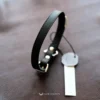 the black obsidian elan discreet collar, folded on a brown leather surface