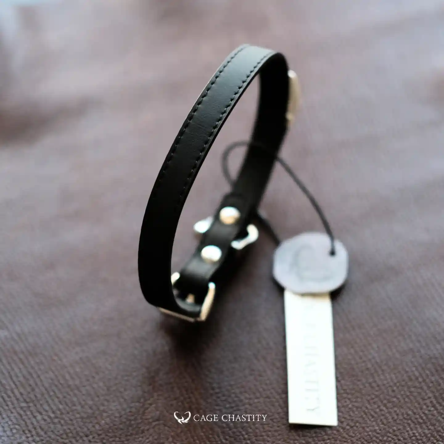 the black obsidian elan discreet collar, folded on a brown leather surface