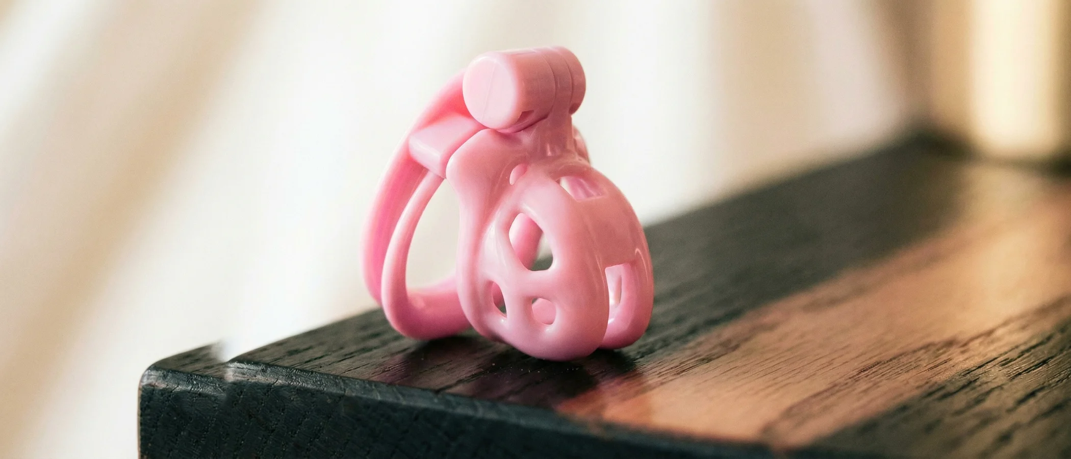 micro chastity cage, a pink tiny cobra on a black desk