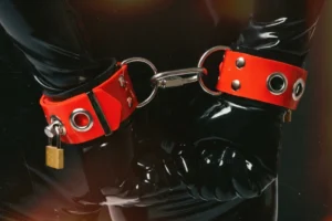 person with hands restrained using red silicone cuffs