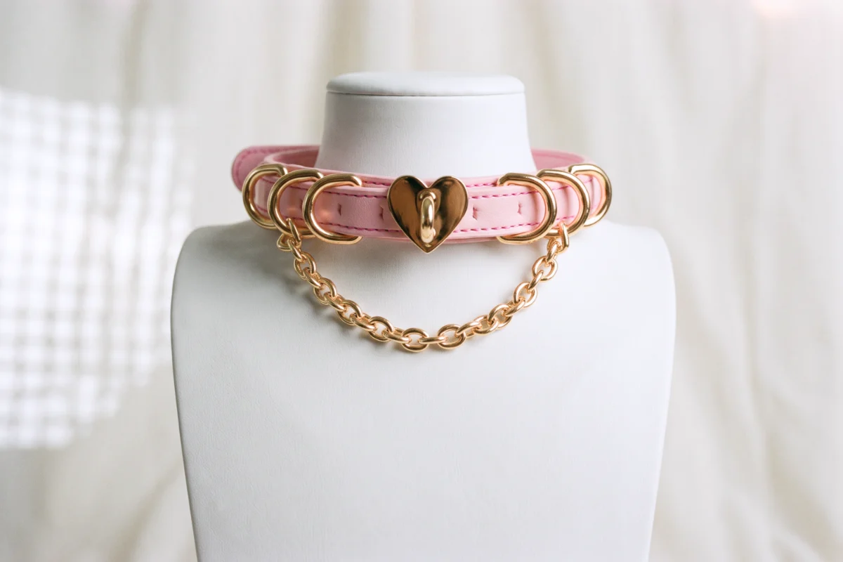 white mannequin wearing a pink sissy collar with gold hardware